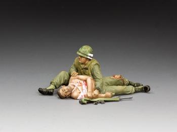 Image of 'Taking Care of a Buddy'--two Vietnam-era figures (one seated cradling a prone wounded comrade)