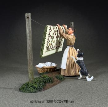 Image of “You Are Really Not Helping!”--Woman Hanging Quilt with Playful Dog, 1855-68--single figure, dog, washing line, basket